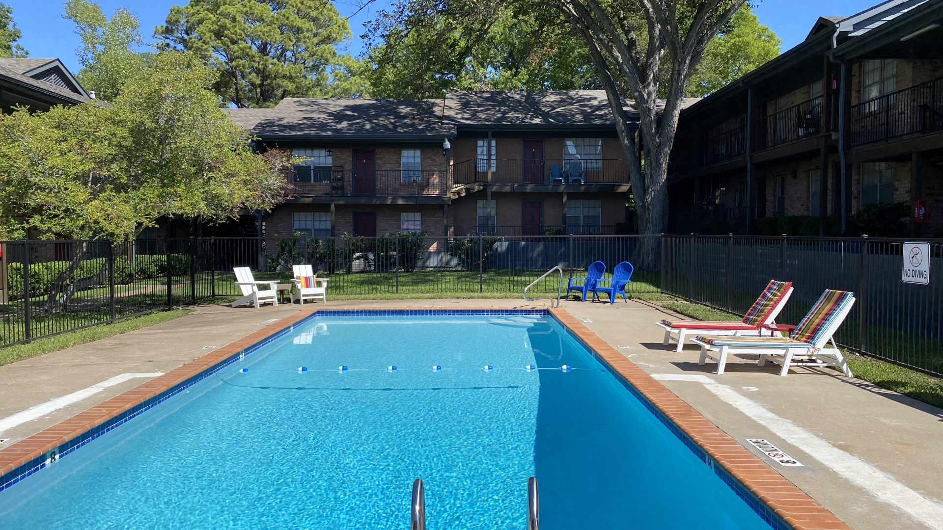 a pool with lounge chairs and a fence around it at The Claridge Apartments